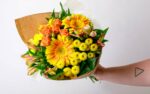 person holding a yellow Mother's Day floral bouquet from Zupan's Markets