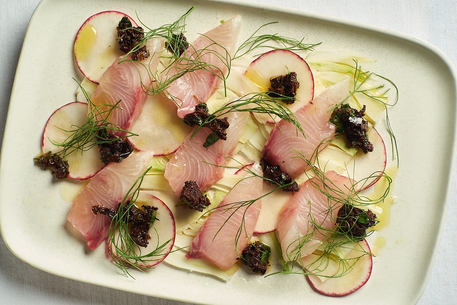 Kanpachi sashimi over shaved fennel topped with olive tapenade