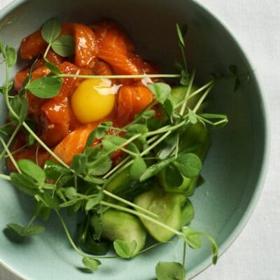 King Salmon sashimi over a bed of pickled cucumbers, micro greens and quail egg