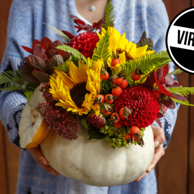 photo of a woman holding a pumpkin with a floral arrangement inside