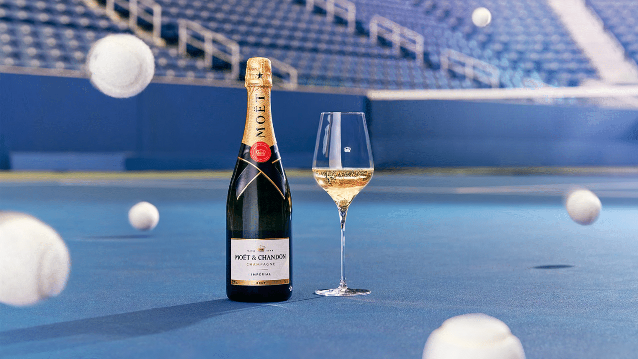 moet chandon brut imperial on a blue tennis court with white tennis balls bouncing around it