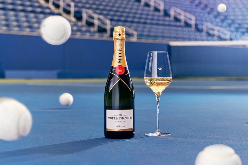 moet chandon brut imperial on a blue tennis court with white tennis balls bouncing around it